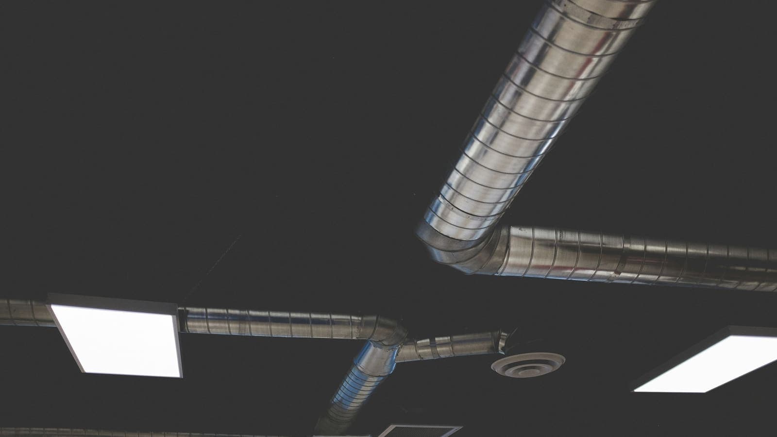 Réseau de gaines de ventilation et bouche d'extraction sous un plafond technique