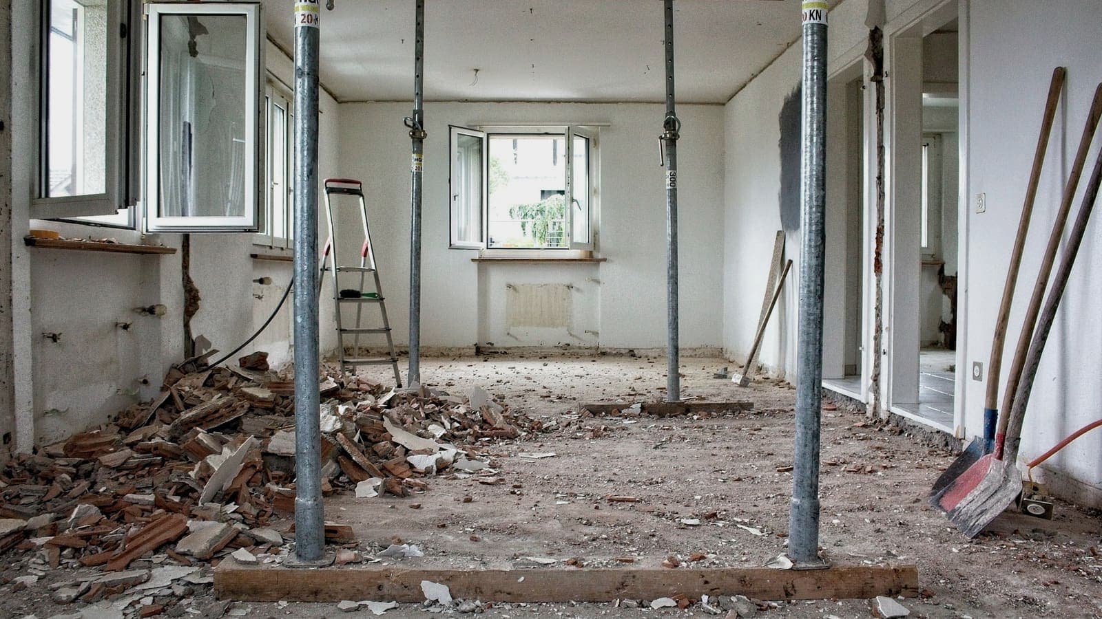Intérieur de logement curé, cloisons déposées et gravats au sol, étais métalliques sous le plancher haut