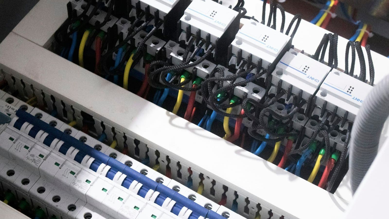 Armoire électrique ouverte, disjoncteurs alignés et câblage repéré dans un immeuble en rénovation