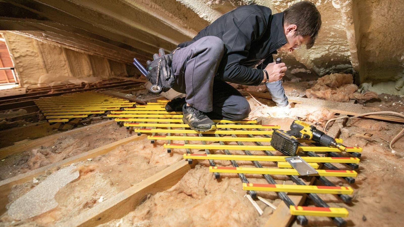 Pose des rails de plancher sur une nappe de laine minérale dans un comble en cours d'isolation