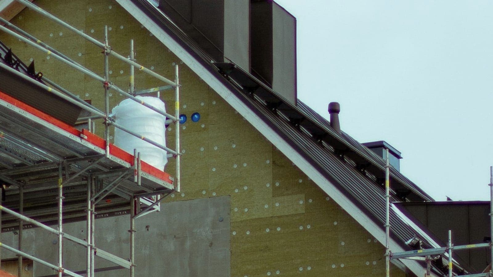 Panneaux de laine minérale fixés par rosaces sur le pignon d'un immeuble, depuis l'échafaudage