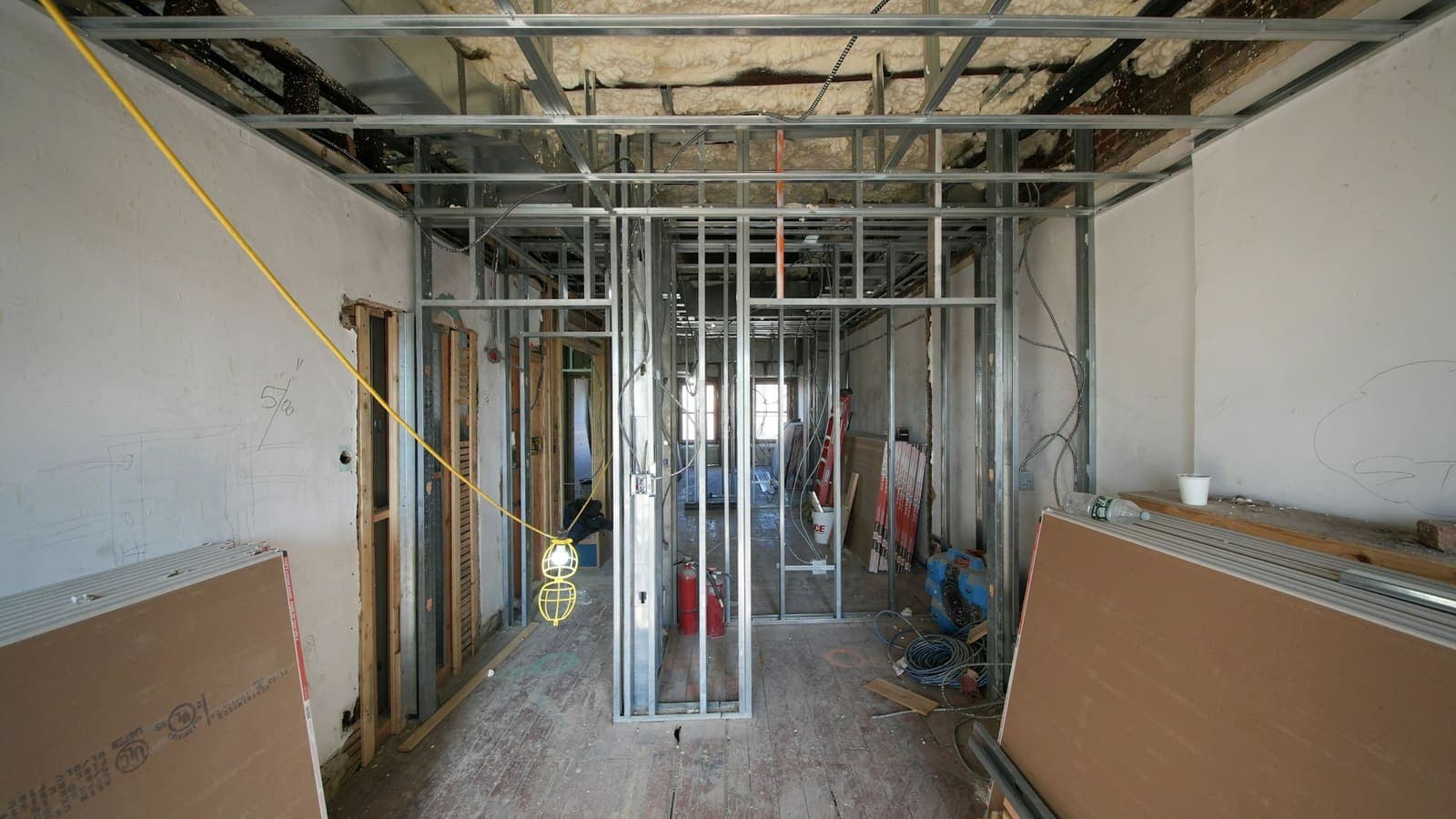 Rails et montants métalliques posés, plaques de plâtre stockées de chant dans un logement en travaux